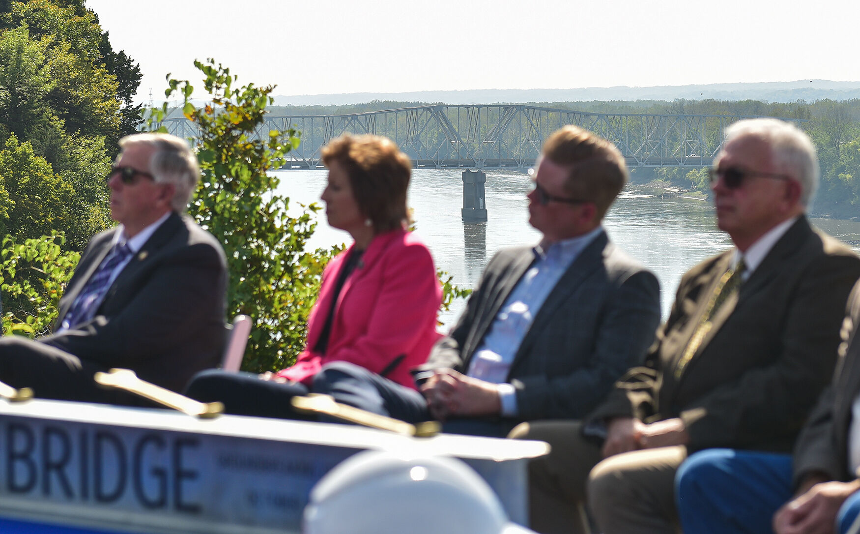 Guests listen to the to Missouri Department of Transportation Director Patrick McKenna speak as the Interstate 70 bridge stands behind them